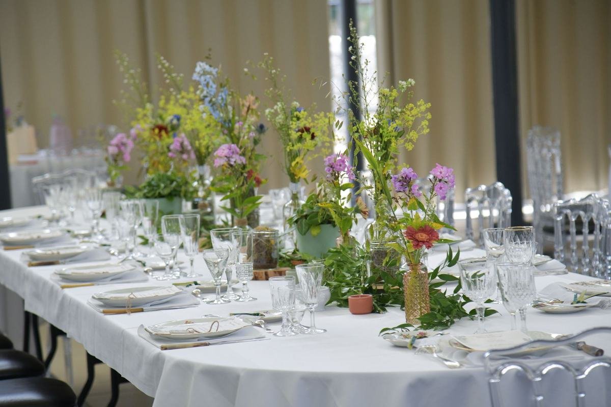 Table dressée de fleurs des champs et de cristal, dans la verdure de la verrière
